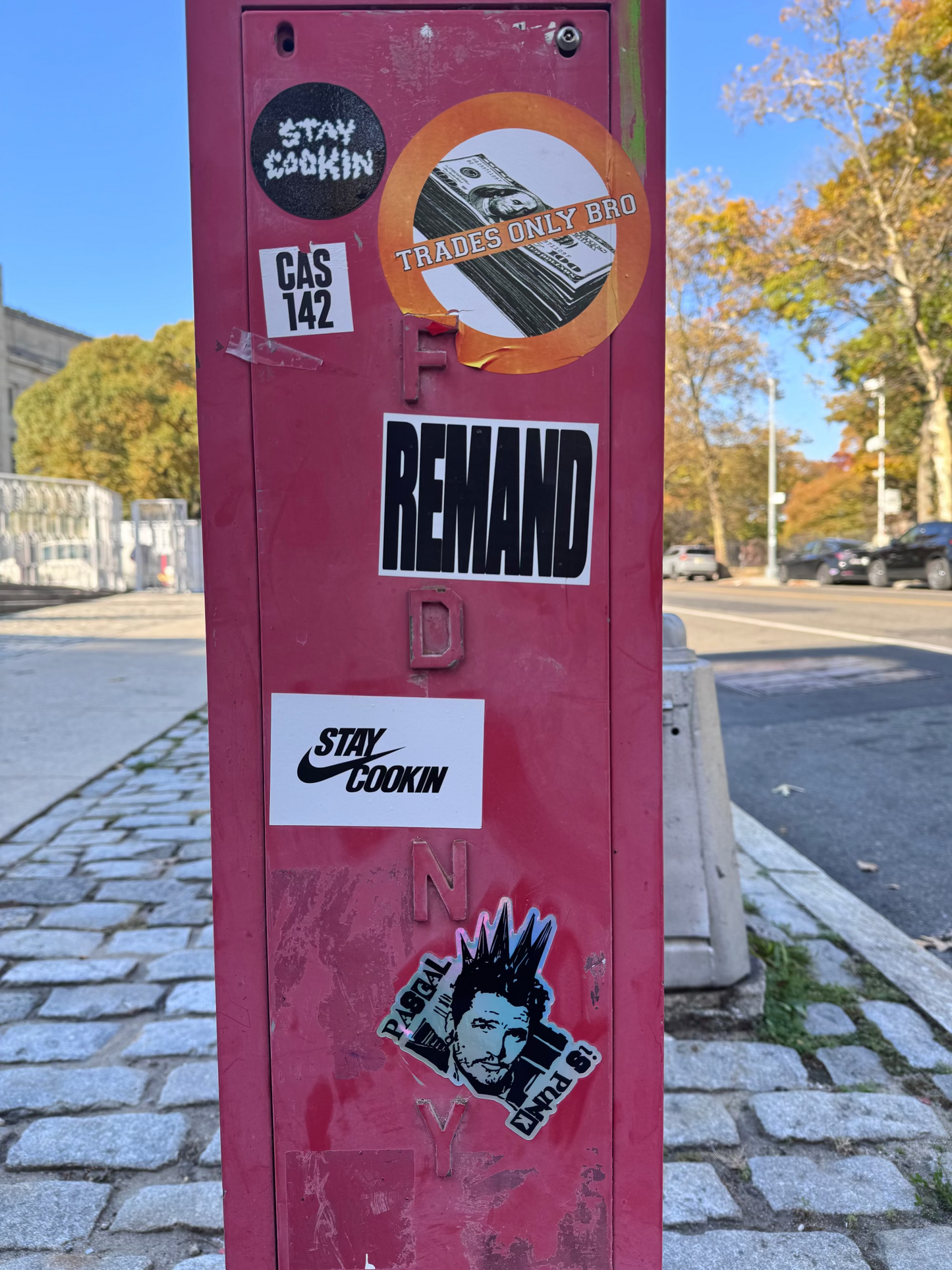 Red metal pole with various stickers on a street background